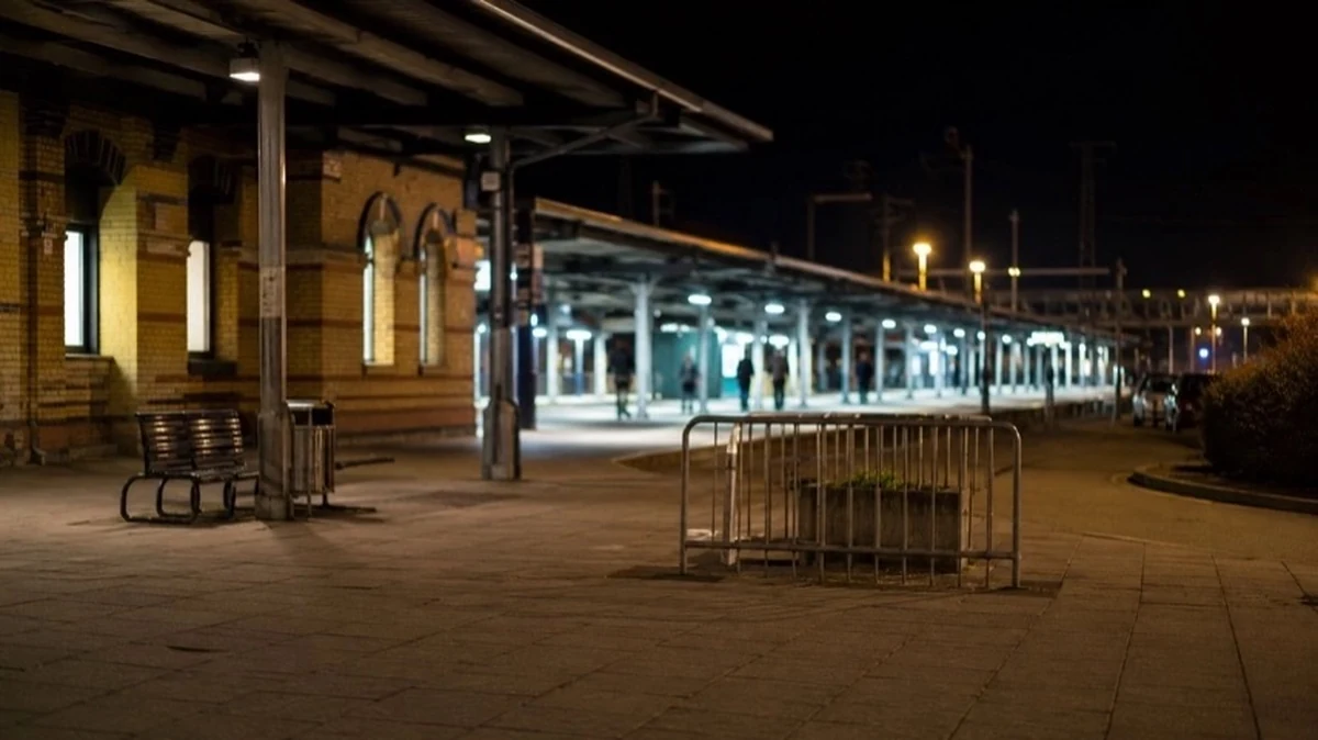Beleuchteter Bahnhofsbereich bei Nacht mit Bahnsteig und unscharfen Personensilhouetten am Wernigerode Hauptbahnhof