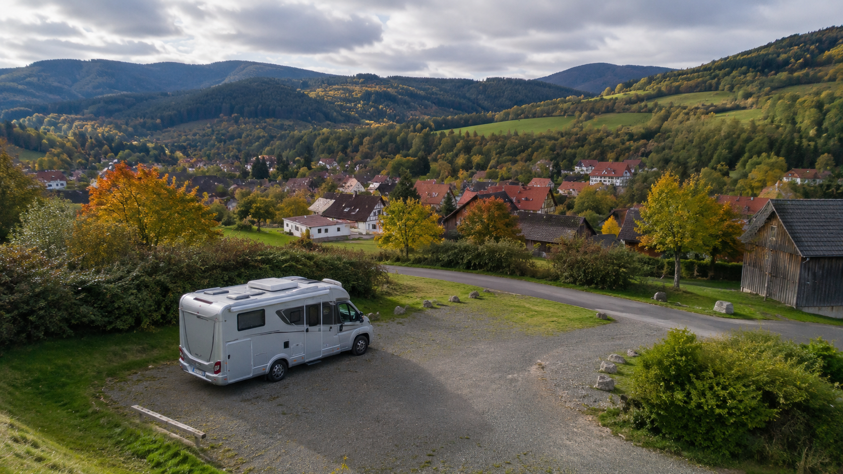 Wohnmobil auf einem kleinen Stellplatz vor bewaldeten Hügeln im Harz
