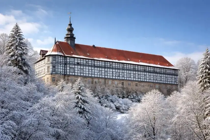 Eingerüstete Fachwerkfassade von Schloss Herzberg am Harz mit Baugerüsten und saniertem Dach bei Tageslicht.